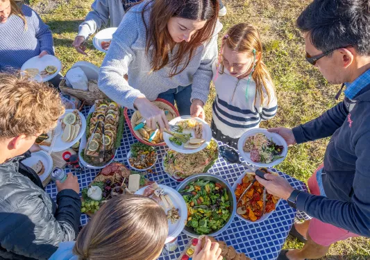 Family plating fish, chicken and salad onto plates