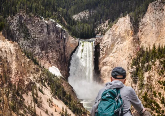 Man looking towards two cliffs and an active waterfall