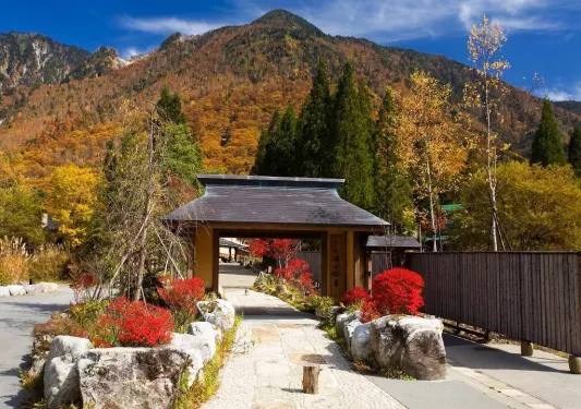 Stone pathway with a wooden archway, surrounded by large boulders and tall mountains in the distance