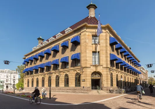 Exterior view of of stone, 2 story building with blue coverings over the windows