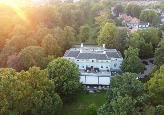 Exterior, sky view of white building surrounded by tall trees