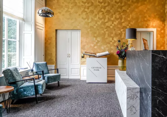 Hotel lobby with blue cushioned chairs and a marble counter to the right
