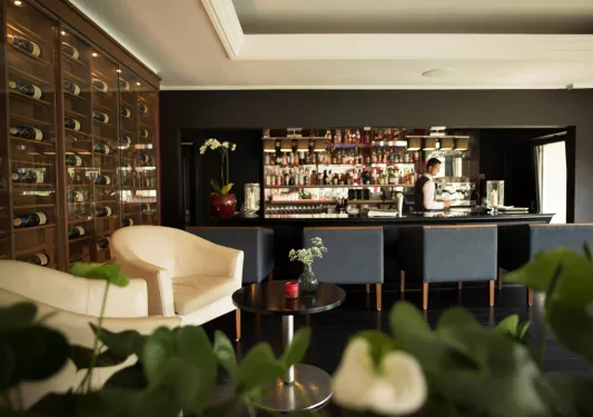 Bar and lounge with a bartender and shelves of alcohol along the walls