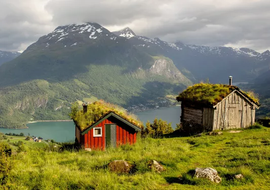 Red building on top of a cliff with a lake in the distance