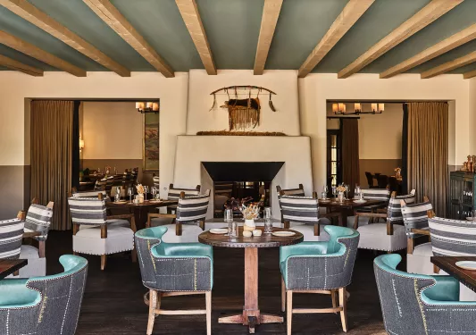 Indoor dining hall with green and gray cushioned chairs and a fireplace in the center
