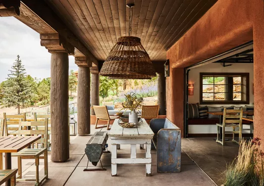 Outdoor patio with wooden chairs and tables, with large wooden pillars on the left