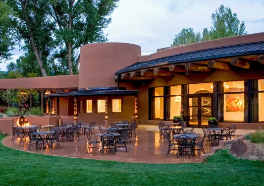 Exterior view of red clay building with dining tables and chairs outdoors