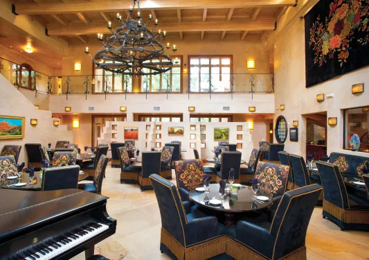 Indoor dining hall with large, blue chairs and a piano to the left
