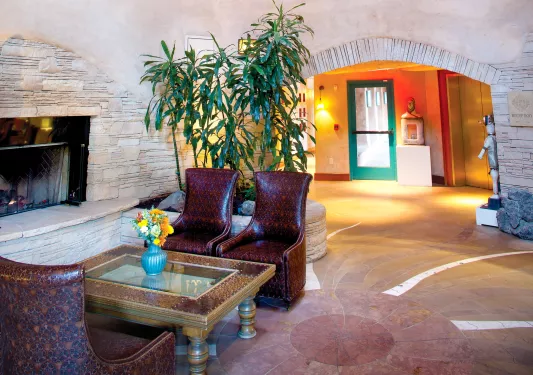 Lobby and seating area with red, leather chairs in front of a stone fireplace
