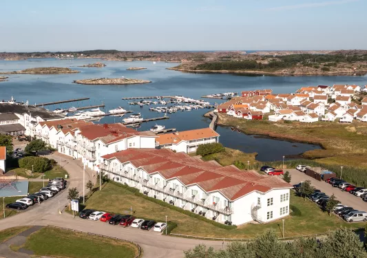 White hotel buildings with brown roofs next to a port with a large lake in the background