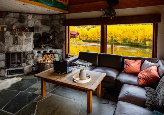 Room with a stone fireplace and leather sofa in front,  with a wooden table in the center