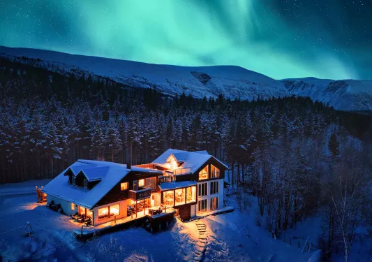 Large cabin-style building with snow and a forest in the background