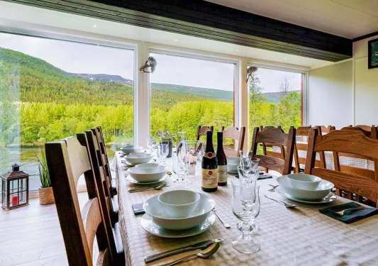Dining room with a large table and wine glasses along the table, with large windows in the back