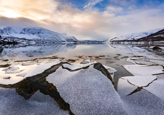 Large lake in the middle of a snowy valley with snow-capped mountains