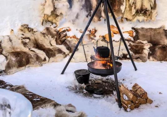 Kettle over a campfire and grill in the middle of a snowy field