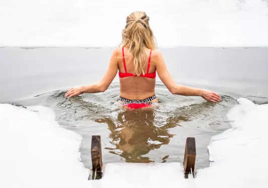 Back of a woman wearing a red bikini standing in a hot spring