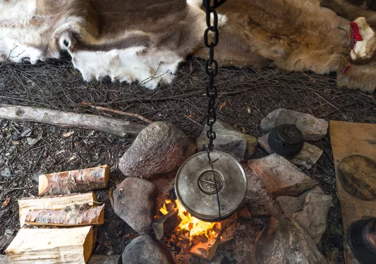 Stone fire pit with a cast iron pan hanging over a fire
