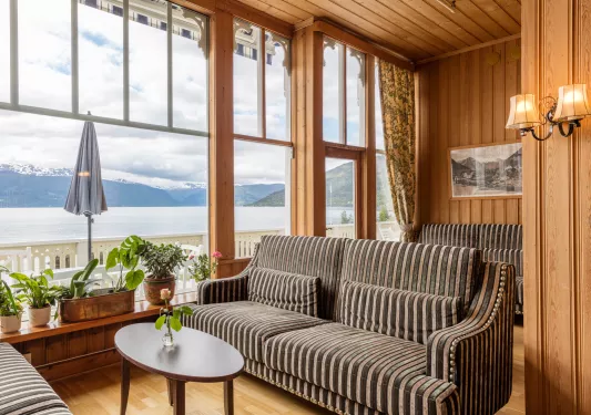 Corner room with wooden walls and striped couches, with a lake outside
