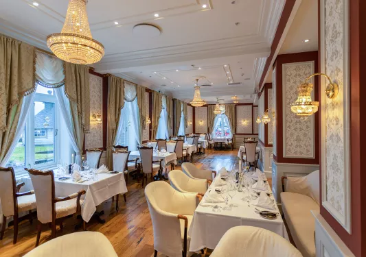 Dining hall with tables with linens and cushioned chairs