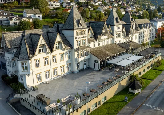 Exterior sky view of white and gray hotel building with a stone patio outdoors