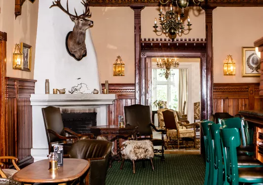 Bar and lounge with cushioned chairs surrounding a fireplace