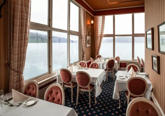 Restaurant in a corner room with large windows, red chairs and white tables