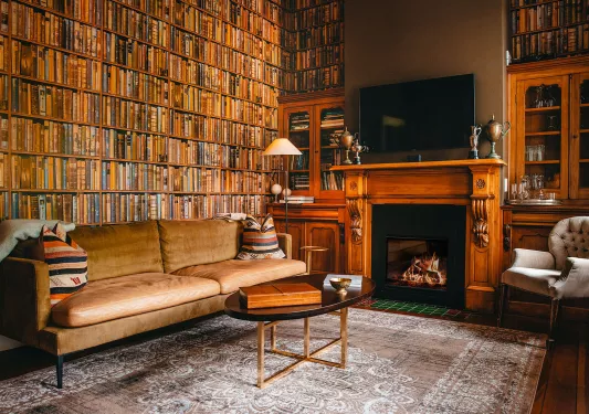 Library room with beige couch and fireplace to the right