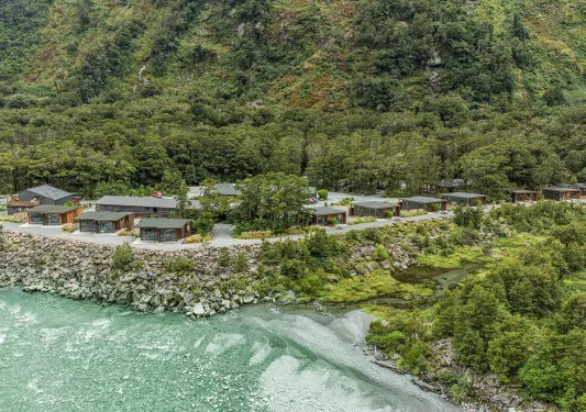 Cabin buildings surrounded by thick forest, with the ocean to the left