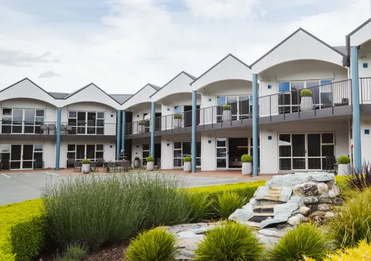 Exterior view of white hotel building with rooms and large windows