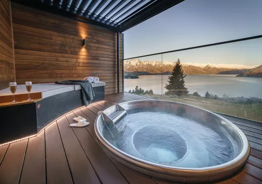 Outdoor hot tub overlooking a lake and snow-capped mountains