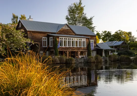 Exterior view of large wooden building with a lake in front