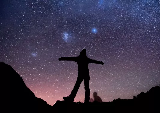 Silhouette of woman with her arms open with the stars in the sky