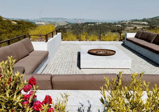 Rooftop patio with a large, brown couch and fire pit in the center
