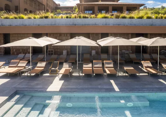 Outdoor pool with reclining, beige chairs surrounding