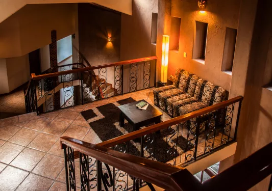 Indoor seating area with staircases on either side, with a patterned couch and black table