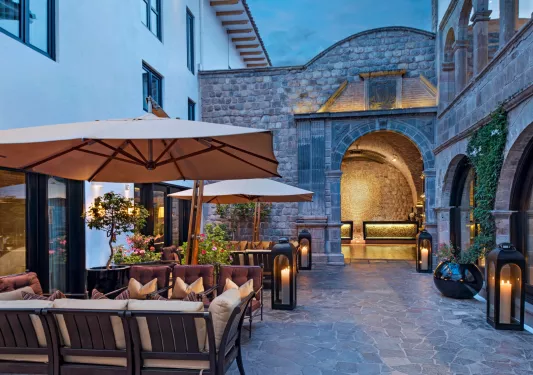 Outdoor patio with stone archways to the right and cushioned seats to the left