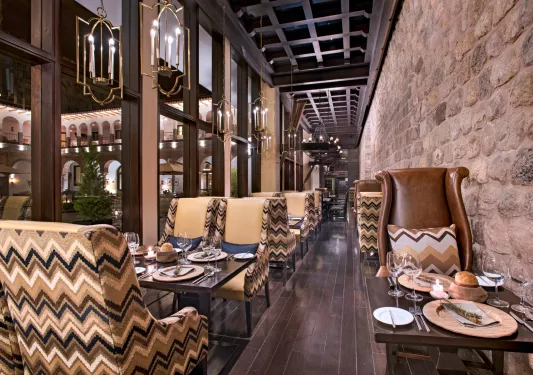 Narrow hallway with dining tables and leather chairs, with large windows to the left