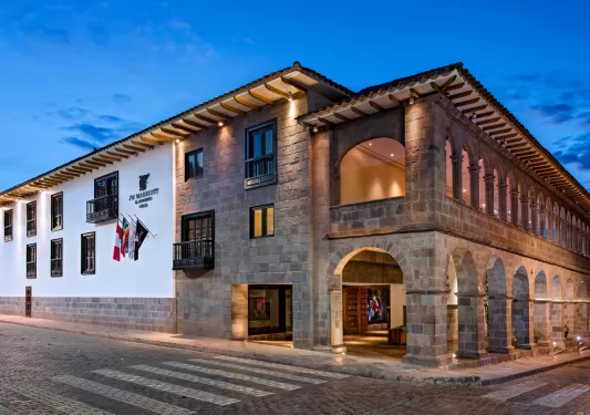 Exterior view of stone hotel building with small archways and empty road in front