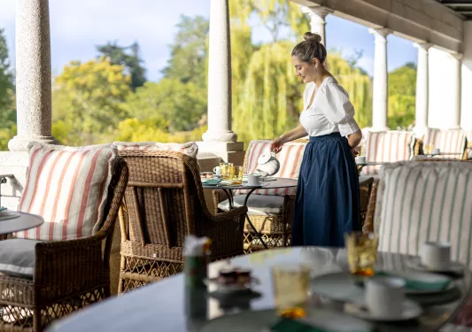 Woman pouring tea into cups on a dining table