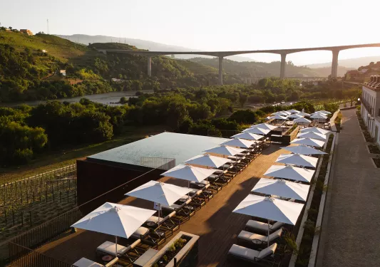 Outdoor patio with a pool, reclining chairs and a view of a tall bridge