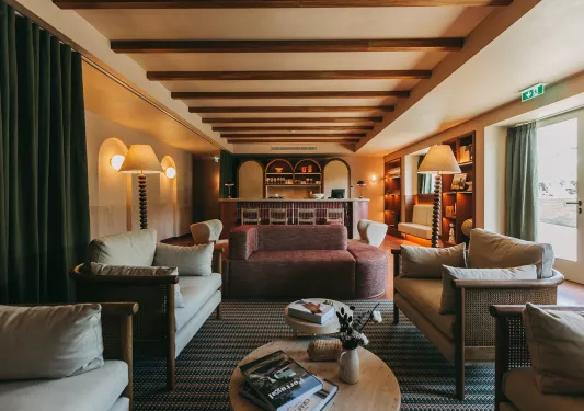 Indoor seating area and lounge with cushioned sofas and green curtains