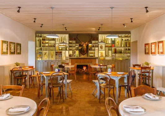 Dining area with wooden tables and chairs, with a deer head hanging on the wall