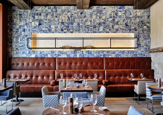 Restaurant dining hall with large, leather sofas and wine glasses on each table