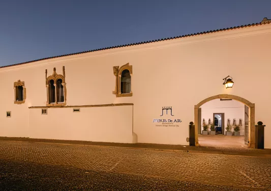 Exterior view of large, white building with gold window coverings and a large gate