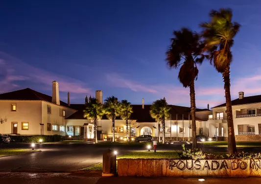 Outdoor view of white hotel building illuminated with the sunset in the background
