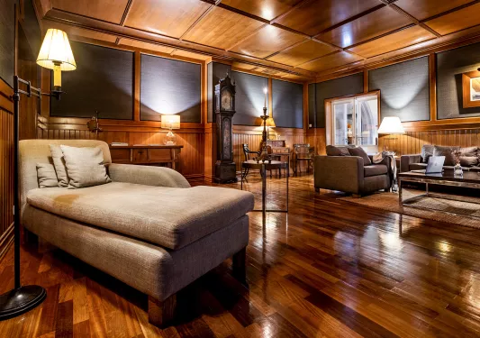 Lounge with wood flooring and walls, with lounge couches in the room