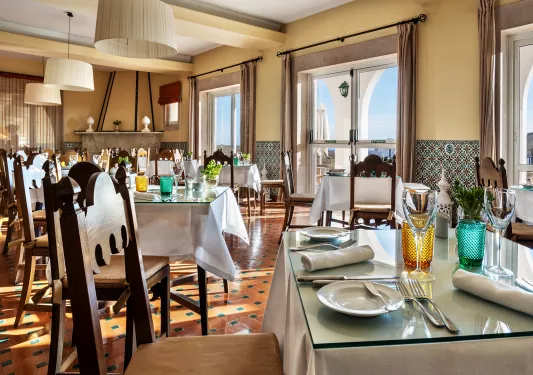 Restaurant with white dining tables and large windows in the background