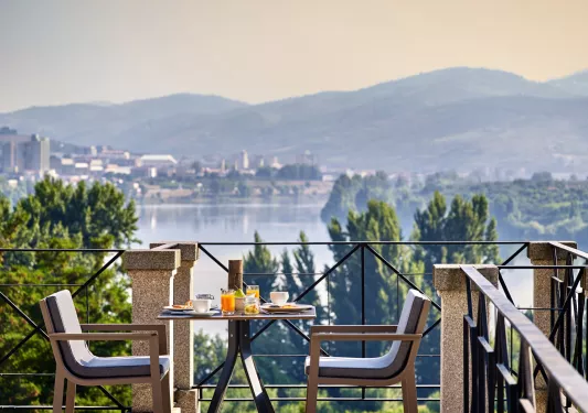 Rooftop patio with a dining tale and chairs, looking out towards a large lake