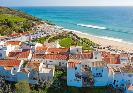 Sky view of white and brown houses next to the beach shore