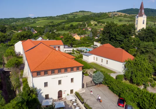 Exterior sky view of large white hotel buildings with red roofing, and a valley in the background